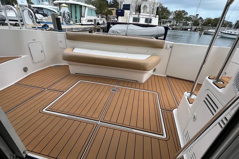 Slide: The Image of 2000 Sea Ray 400 Sedan Bridge boat deck with cushioned seating and wood finish. - 16