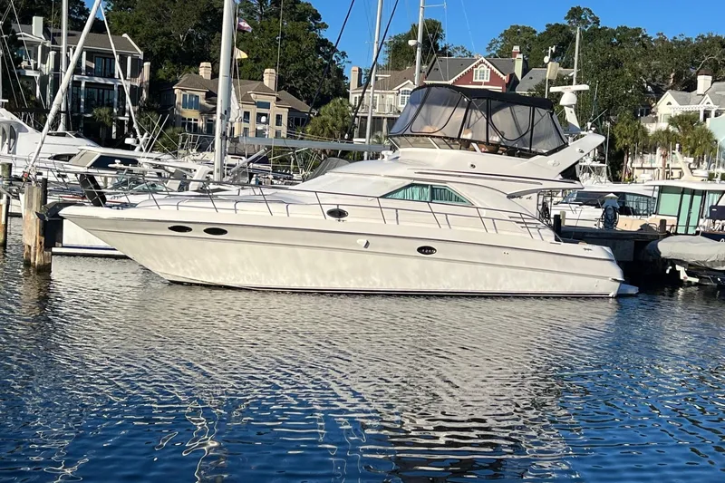 Slide: The Image of 2000 Sea Ray 400 Sedan Bridge yacht docked in a marina, surrounded by water and other boats. - 2