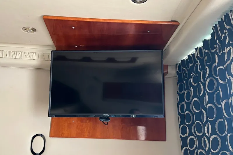 Slide: The Image of Flat-screen TV mounted on a wooden panel inside a 2000 Sea Ray 400 Sedan Bridge. - 41