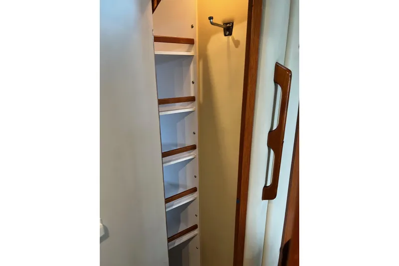 Slide: The Image of Storage shelves inside 2000 Sea Ray 400 Sedan Bridge yacht, featuring wooden accents and a hook. - 52