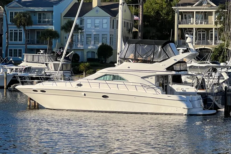 Slide: The Image of 2000 Sea Ray 400 Sedan Bridge yacht docked in a marina, surrounded by waterfront homes. - 74