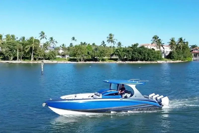 Slide: The Image of 2023 Mystic Powerboats M3800 cruising on a scenic waterway with palm trees in the background. - 1
