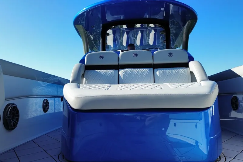Slide: The Image of 2023 Mystic Powerboats M3800 with luxurious seating and sleek design under clear blue sky. - 17