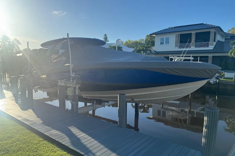 Slide: The Image of 2023 Mystic Powerboats M3800 covered, docked by waterfront home in sunlight. - 31