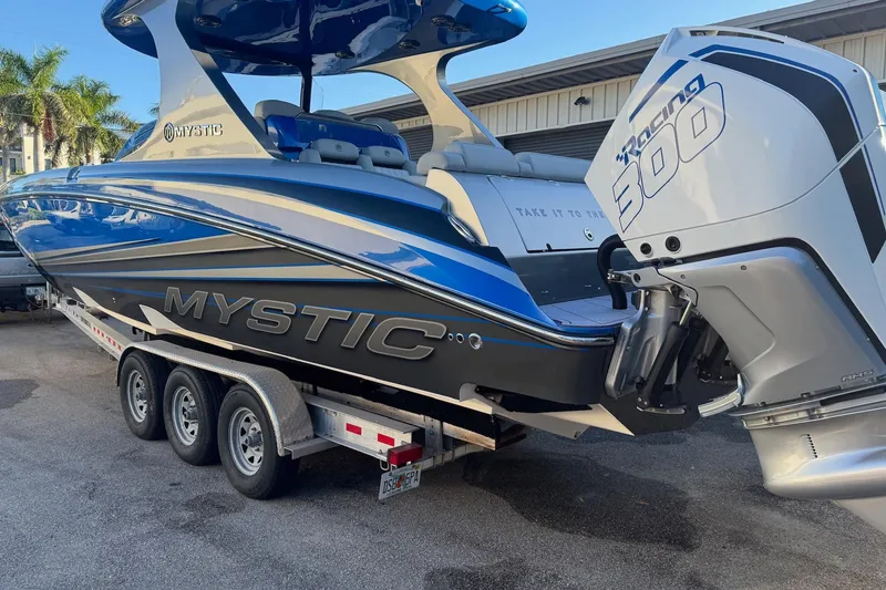 Slide: The Image of 2023 Mystic Powerboats M3800 on trailer, featuring sleek blue design and powerful engine. - 33