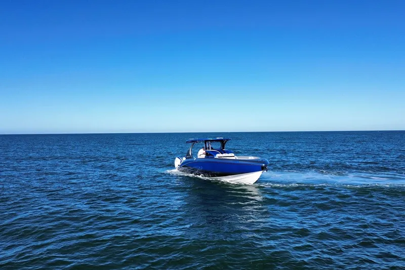 Slide: The Image of 2023 Mystic Powerboats M3800 cruising on open blue ocean under clear sky. - 6