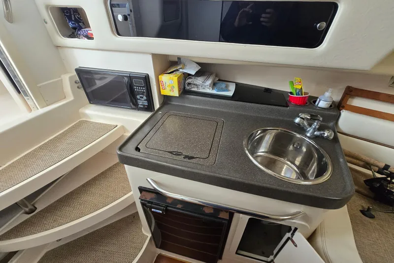 Slide: The Image of 2005 Grady-White Marlin 300 boat interior with kitchenette, sink, and microwave. - 29