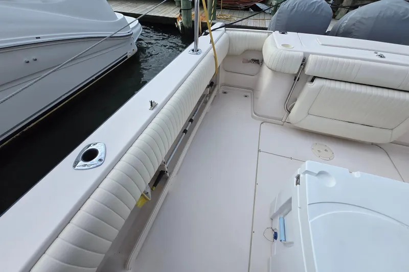 Slide: The Image of 2005 Grady-White Marlin 300 boat interior with cushioned seating and docked alongside another vessel. - 35