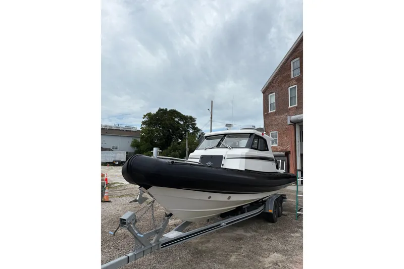 Slide: The Image of 2020 Protector 310 Targa boat on trailer, parked near brick building under cloudy sky. - 10