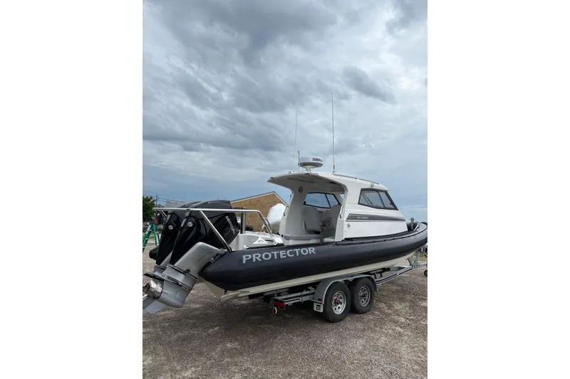 Slide: The Image of 2020 Protector 310 Targa boat on trailer under cloudy sky. - 2