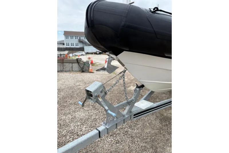 Slide: The Image of 2020 Protector 310 Targa boat on trailer, secured with chains, in a gravel lot. - 5