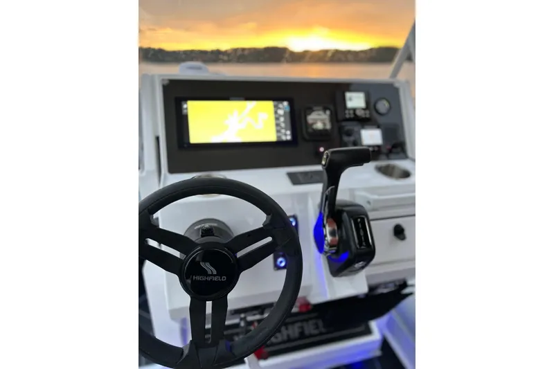 Slide: The Image of Highfield Sport 660 boat dashboard with steering wheel and controls, sunset view, 2025 model. - 3