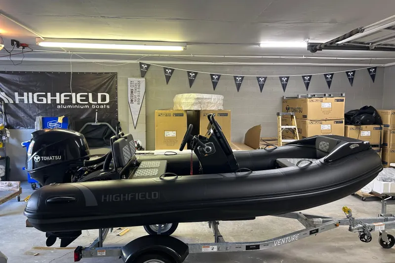 The Image of 2025 Highfield Sport 360 boat in garage, featuring Tohatsu engine and Highfield branding. - 1