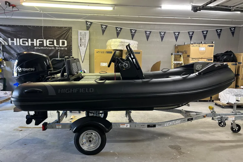 Slide: The Image of 2025 Highfield Sport 360 inflatable boat with Tohatsu engine on trailer in garage. - 10