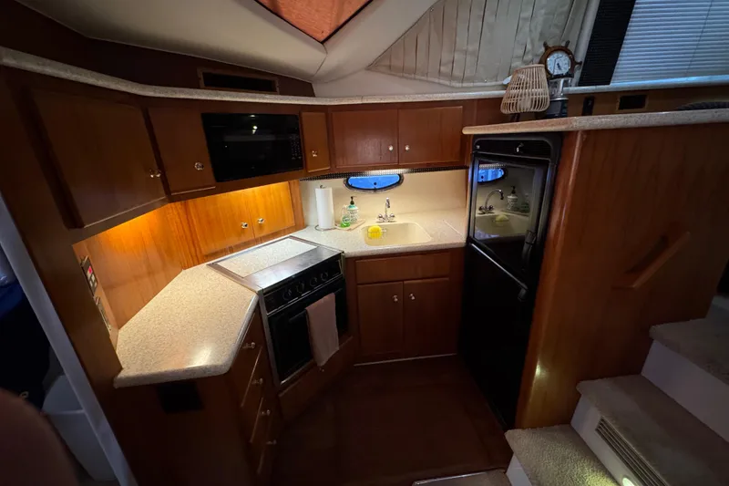 Slide: The Image of Interior of 2000 Carver 406 Aft Cabin Motor Yacht kitchen with wood cabinetry and appliances. - 16
