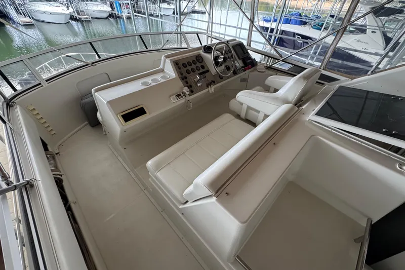 Slide: The Image of 2000 Carver 406 Aft Cabin Motor Yacht helm with white seating and control panel. - 9