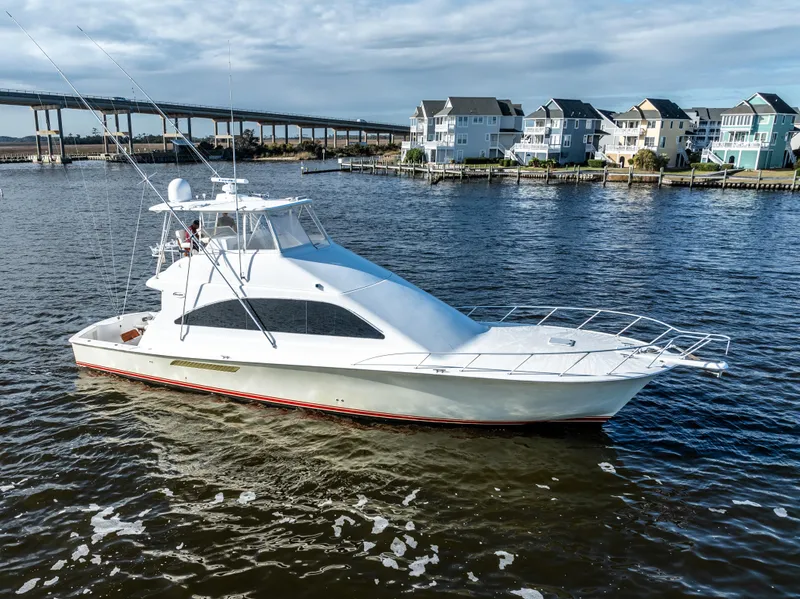 Slide: The Image of 2006 Ocean 57 yacht cruising near waterfront homes and a bridge. - 2