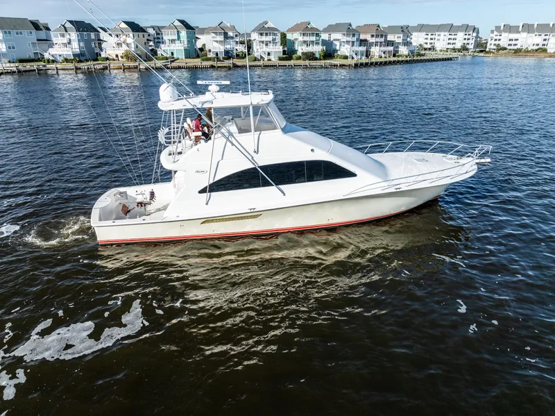 Slide: The Image of 2006 Ocean 57 yacht cruising on a scenic waterfront with houses in the background. - 3