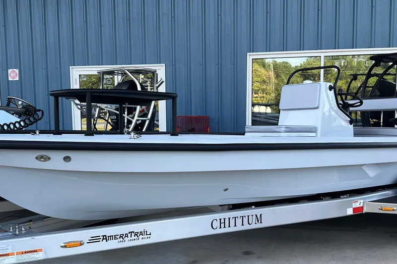 Slide: The Image of 2026 Chittum Skiffs 21 Islamorada boat on AmeraTrail trailer, parked by blue building. - 2