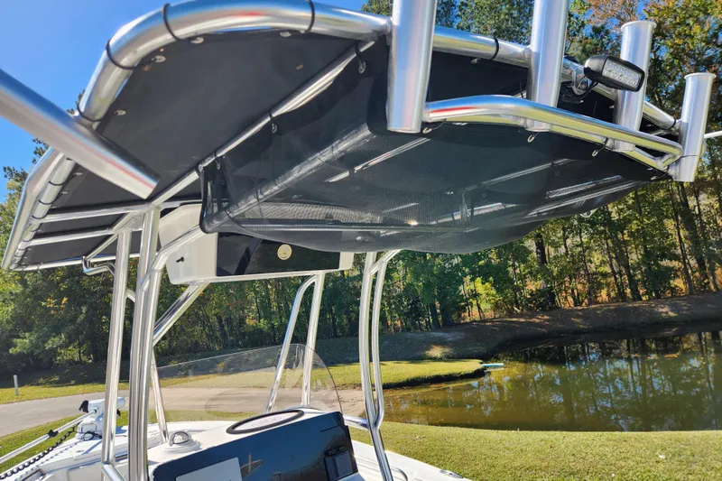 Slide: The Image of 2024 Sea Hunt Ultra 229 boat with T-top and rod holders by a scenic pond. - 12