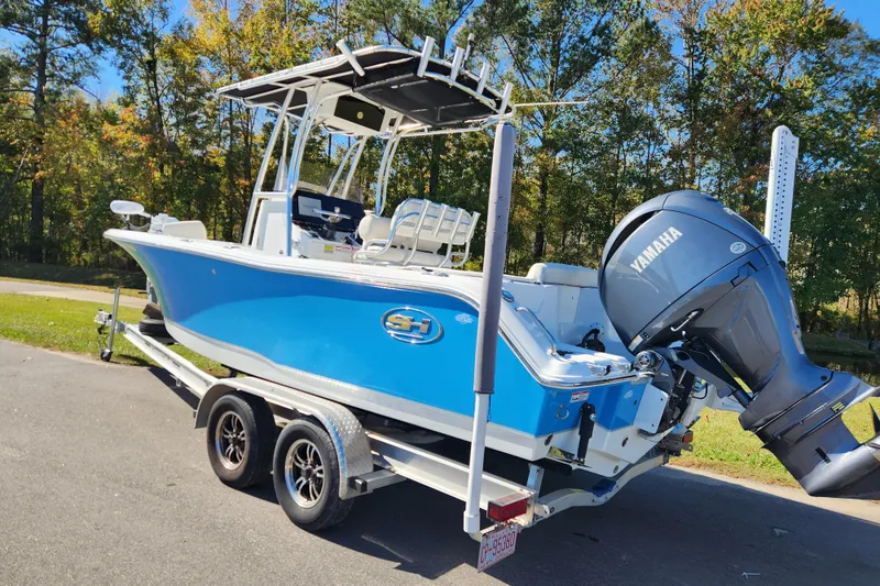 Slide: The Image of 2024 Sea Hunt Ultra 229 boat on trailer with Yamaha engine, parked outdoors. - 2
