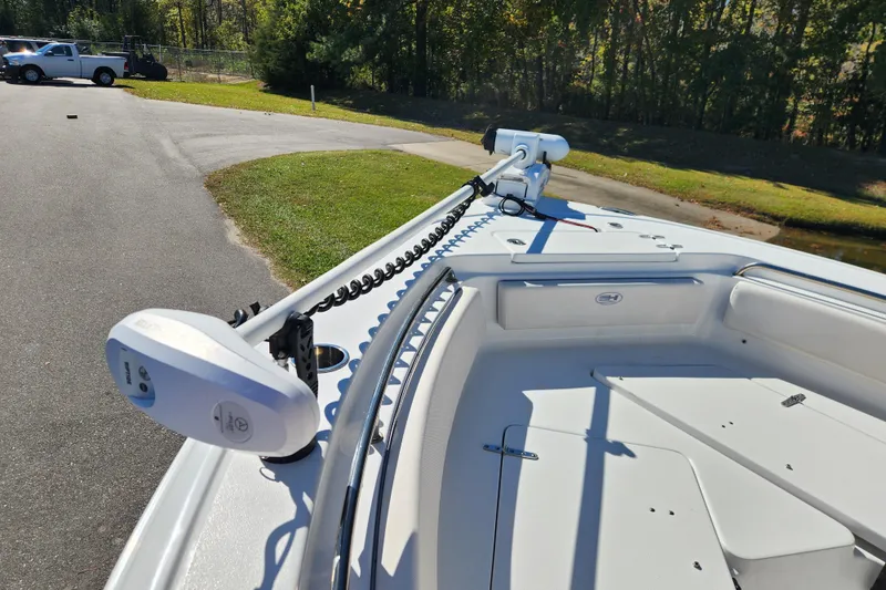 Slide: The Image of 2024 Sea Hunt Ultra 229 boat with trolling motor on deck, parked near grassy area. - 8