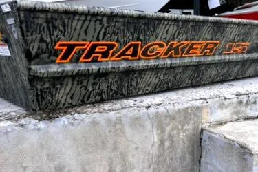 The Image of 2026 Tracker Grizzly 15 Jon boat with camouflage design on concrete surface. - 0
