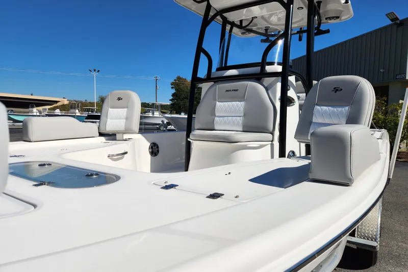 Slide: The Image of 2019 Sea Pro 248 Bay boat interior with white seating and console, under clear blue sky. - 11