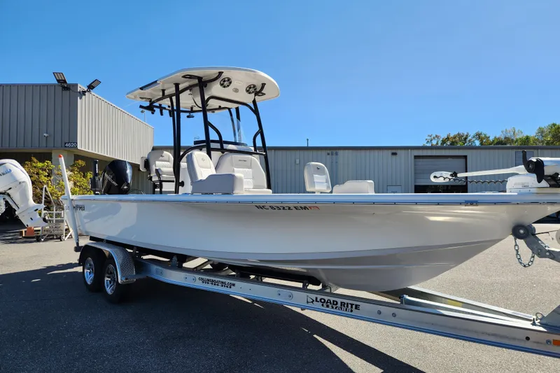 Slide: The Image of 2019 Sea Pro 248 Bay boat on trailer, parked outside a warehouse under clear blue sky. - 7