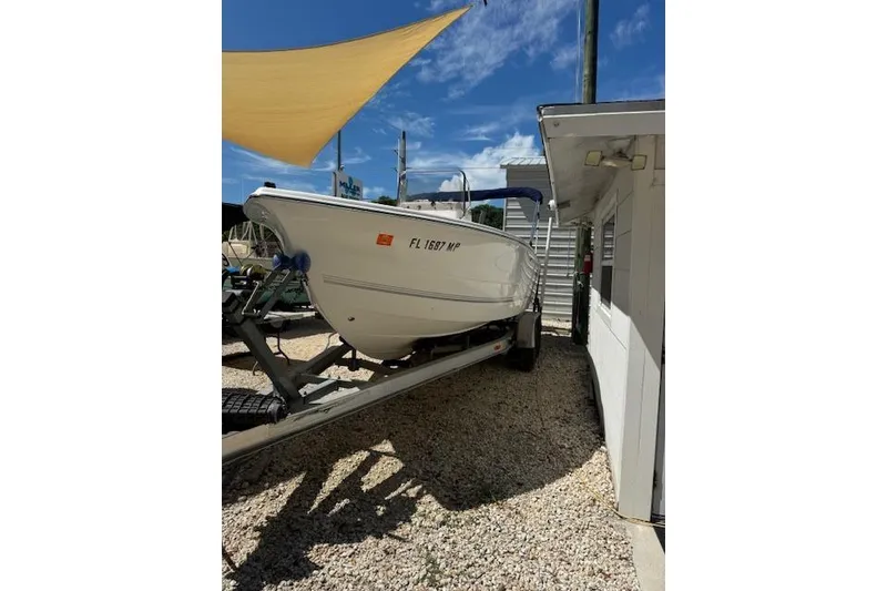 Slide: The Image of 2003 Sea Pro 206 Center Console boat on trailer, parked beside a building under a sunny sky. - 3