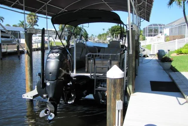 Slide: The Image of 2018 Regency 220 DL3 pontoon boat docked with canopy and powerful outboard motor. - 3