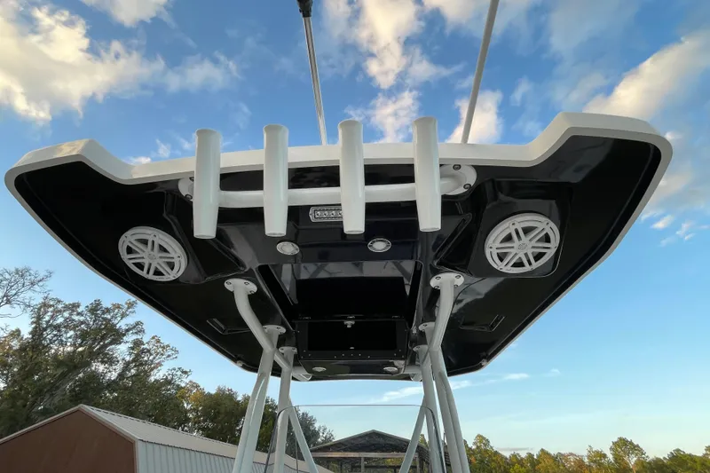 Slide: The Image of 2022 Blackfin 252 CC boat roof with rod holders and speakers against blue sky. - 28