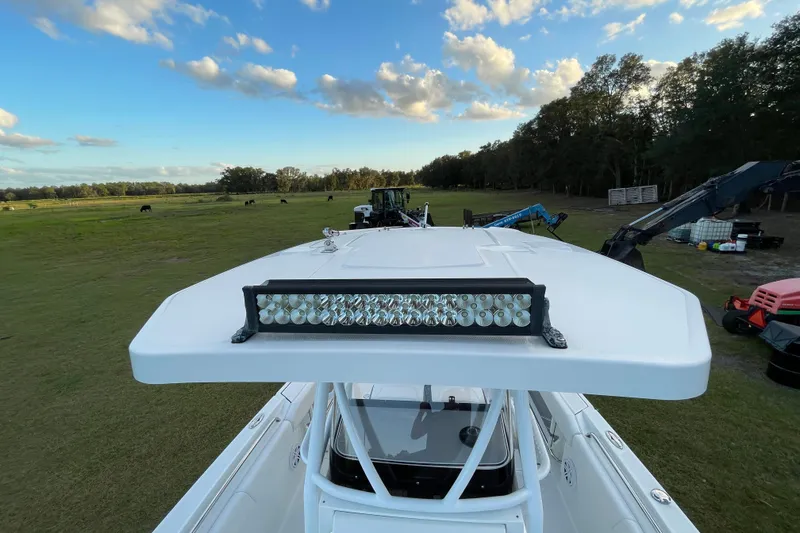 Slide: The Image of 2022 Blackfin 252 CC boat with LED light bar, parked on grassy field under blue sky. - 31
