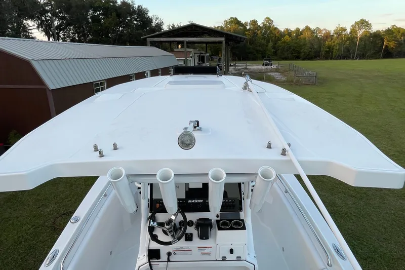 Slide: The Image of 2022 Blackfin 252 CC boat, top view, showcasing helm and rod holders in a grassy setting. - 32