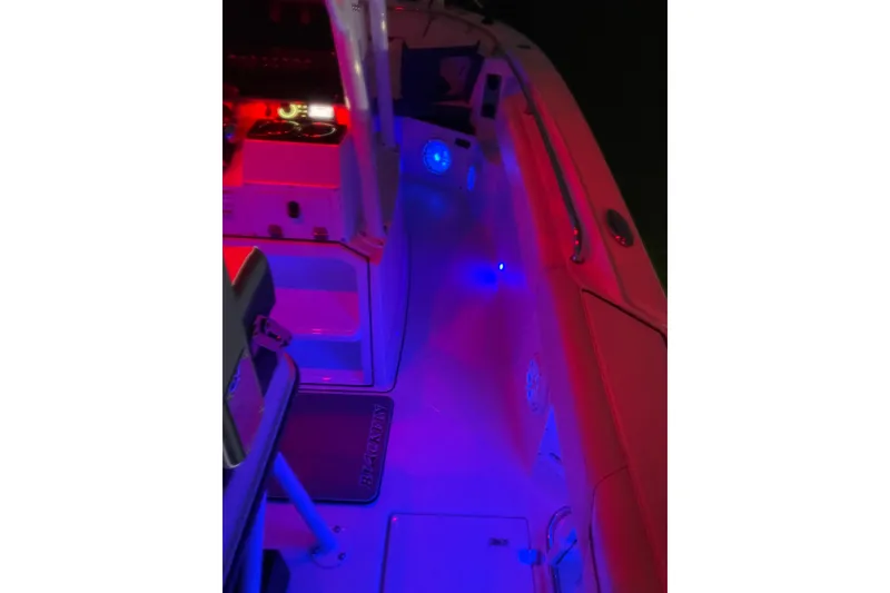 Slide: The Image of 2022 Blackfin 252 CC boat interior with vibrant red and blue LED lighting. - 54
