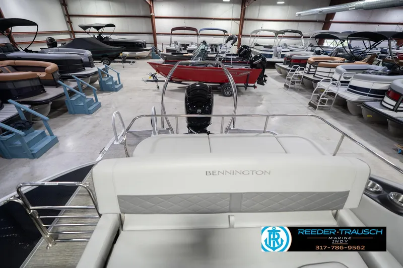 Slide: The Image of 2024 Bennington 23 LSB pontoon boat in showroom with multiple boats displayed. - 18