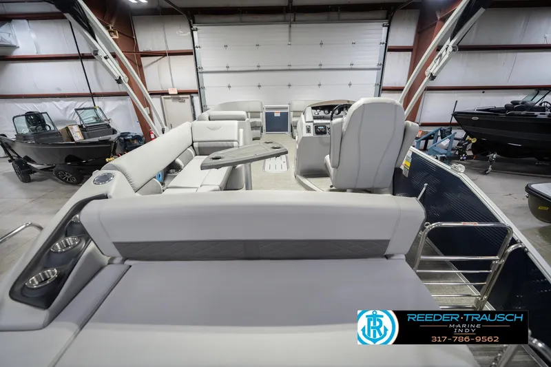Slide: The Image of 2024 Bennington 23 LSB pontoon boat interior in showroom, featuring luxurious seating and helm. - 19