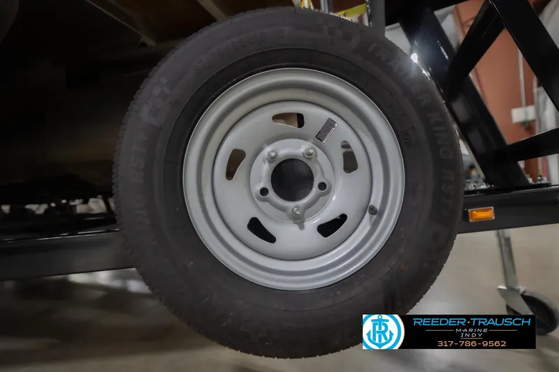 Slide: The Image of 2024 Bennington 23 LSB trailer wheel with tire, displayed indoors at Reeder Trausch Marine. - 68