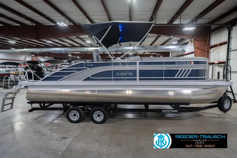 Slide: The Image of 2024 Bennington 23 LSB pontoon boat in showroom, featuring sleek design and trailer. - 7