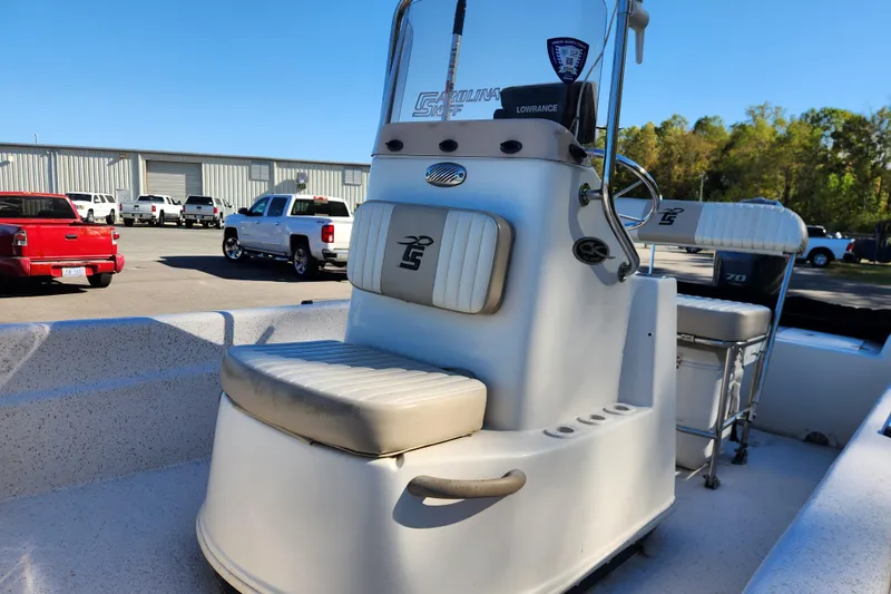 Slide: The Image of 2018 Carolina Skiff 18 JVX CC boat interior with seating and console, parked outdoors. - 10