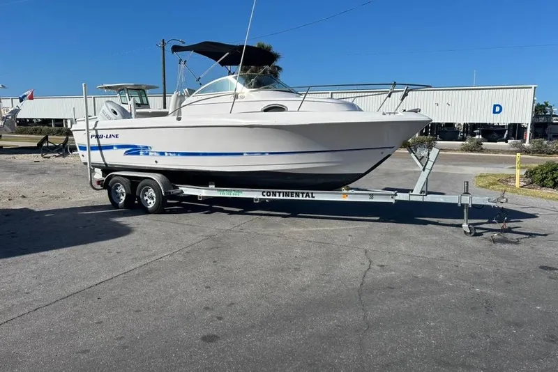Slide: The Image of 2002 Pro-Line 22 Walk boat on trailer, parked outdoors under clear blue sky. - 5
