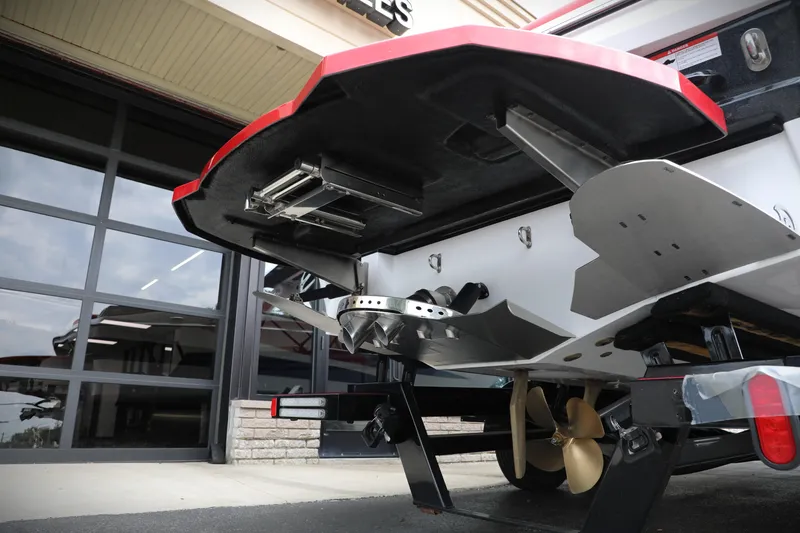 Slide: The Image of 2023 Centurion Fi25 boat underside with propeller and fins, parked near a garage. - 14