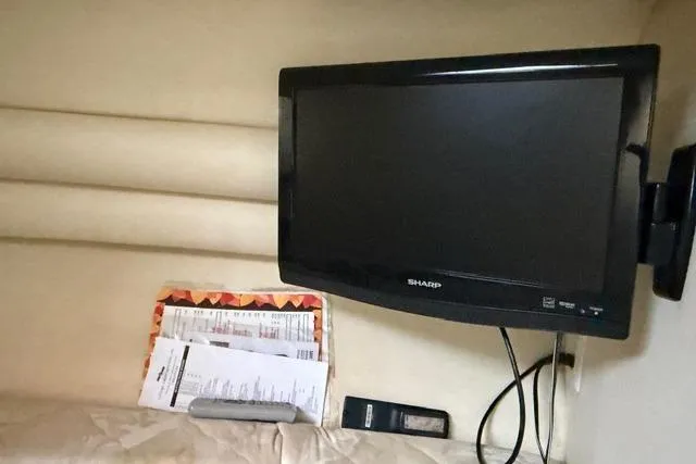 Slide: The Image of 1999 Sea Ray 270 Sundancer cabin with wall-mounted Sharp TV and documents. - 12