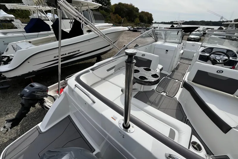 Slide: The Image of 2023 Hurricane SunDeck 235 OB boat interior with seating and steering wheel, docked beside other boats. - 10