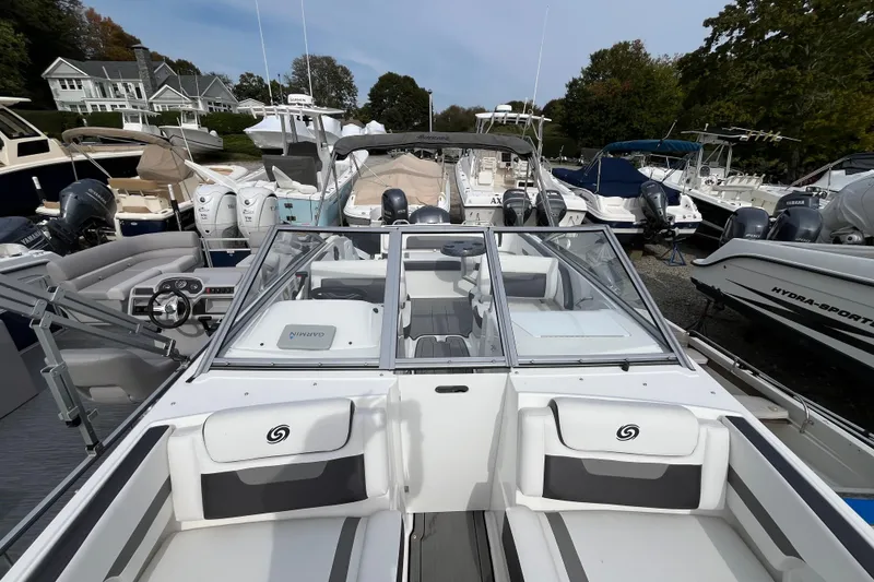 Slide: The Image of 2023 Hurricane SunDeck 235 OB boat docked among other vessels at a marina. - 25