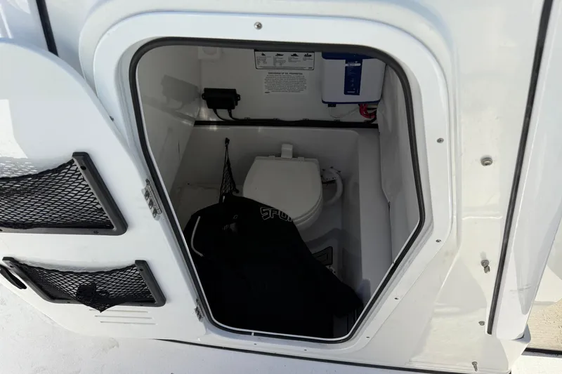 Slide: The Image of 2022 Sportsman Open 262 Center Console boat interior with compact marine toilet. - 12