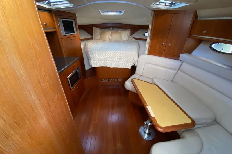 Slide: The Image of 2004 Tiara Yachts 3200 Open interior with bed, seating, and wooden cabinetry. - 10