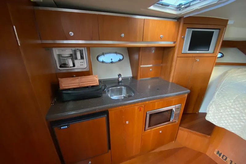 Slide: The Image of 2004 Tiara Yachts 3200 Open interior kitchen with sink, microwave, and wood cabinetry. - 12