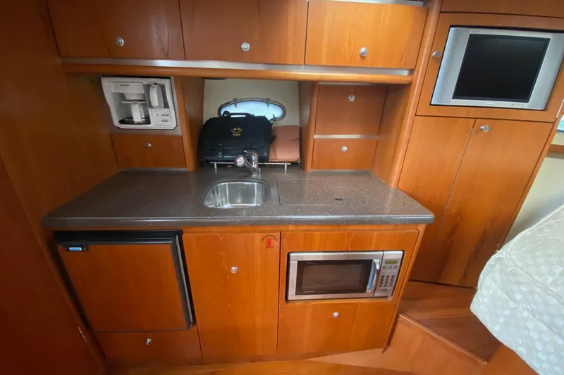 Slide: The Image of 2004 Tiara Yachts 3200 Open galley with sink, microwave, and wooden cabinetry. - 21