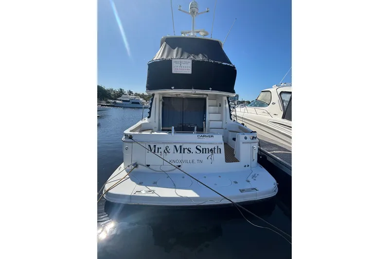 Slide: The Image of 2003 Carver 450 Voyager Pilothouse yacht docked, rear view with "Mr. & Mrs. Smith" name. - 2